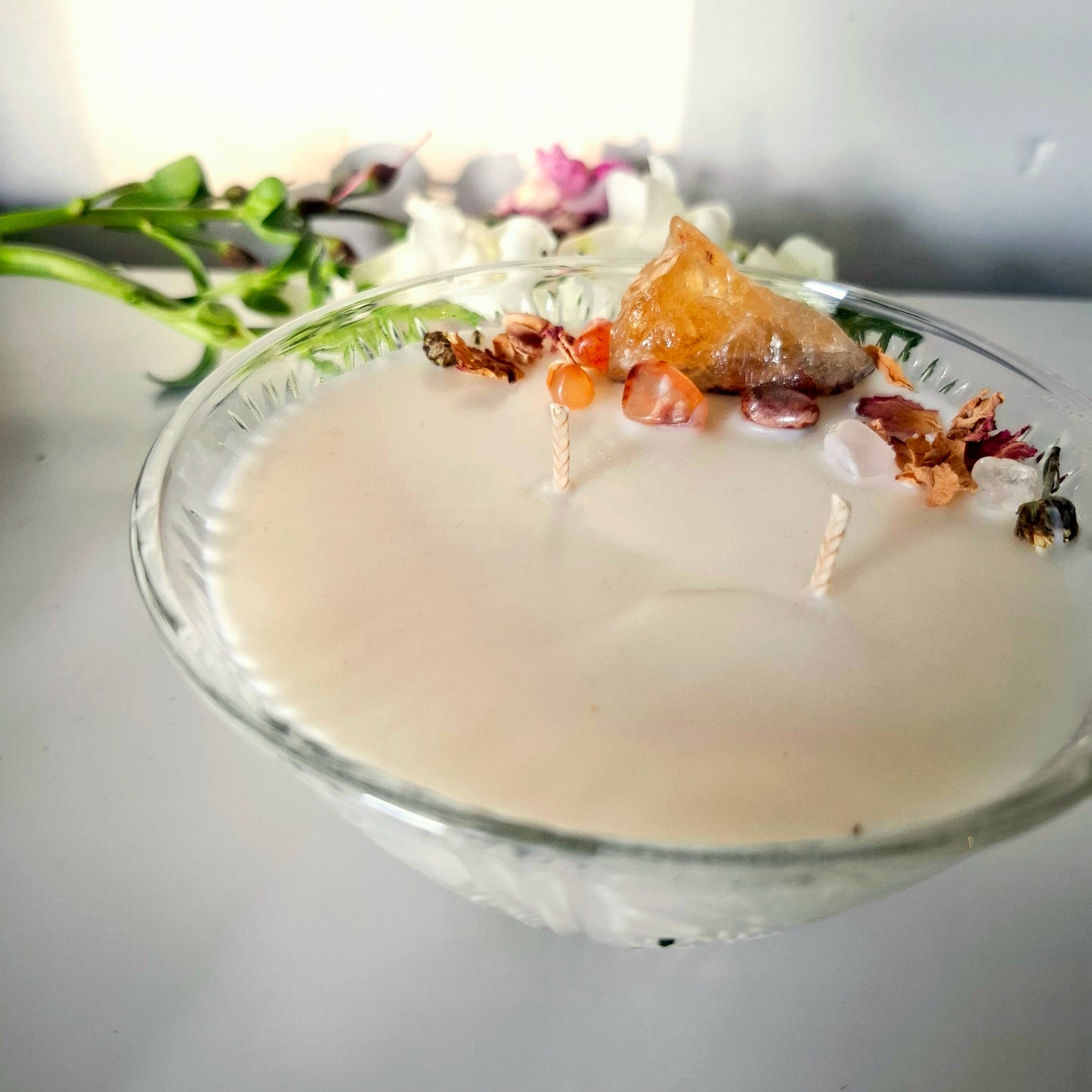Sandalwood and cedar soy wax candle in a glass jar, topped with crystals and dried florals, double cotton wick visible